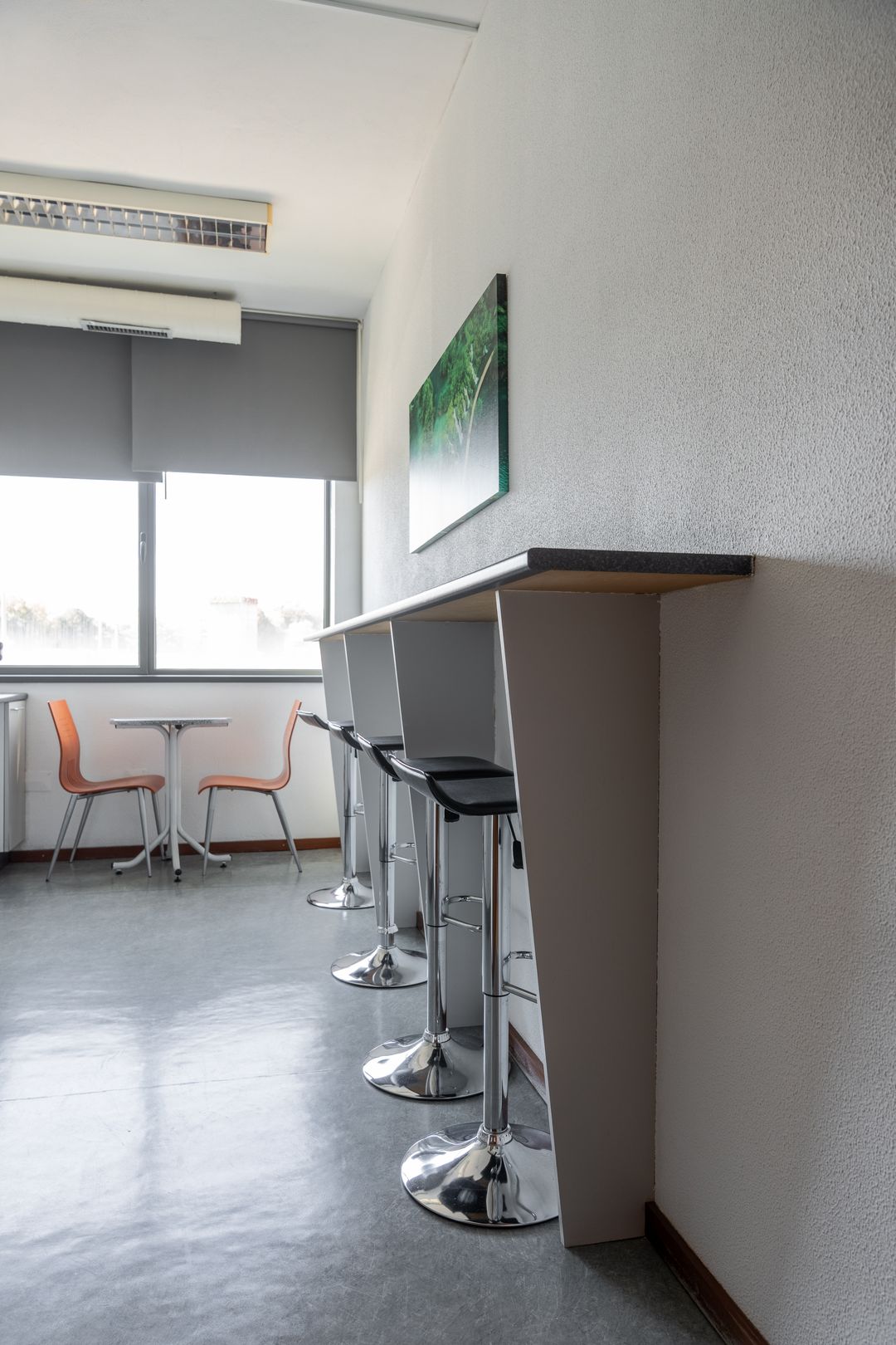 Copa com bancos altos, mesa e cadeiras laranja.