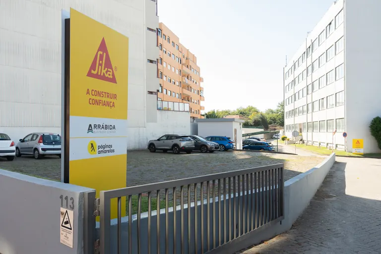 Portão de acesso ao condomínio, com o parque ao fundo.
