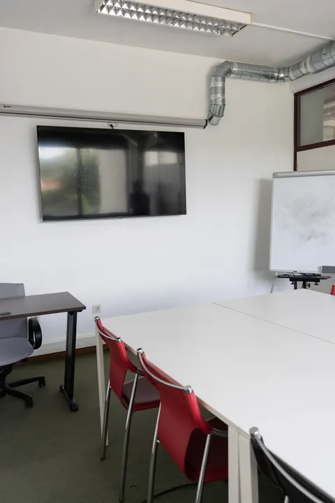 Sala renovada com televisão e flipchart.