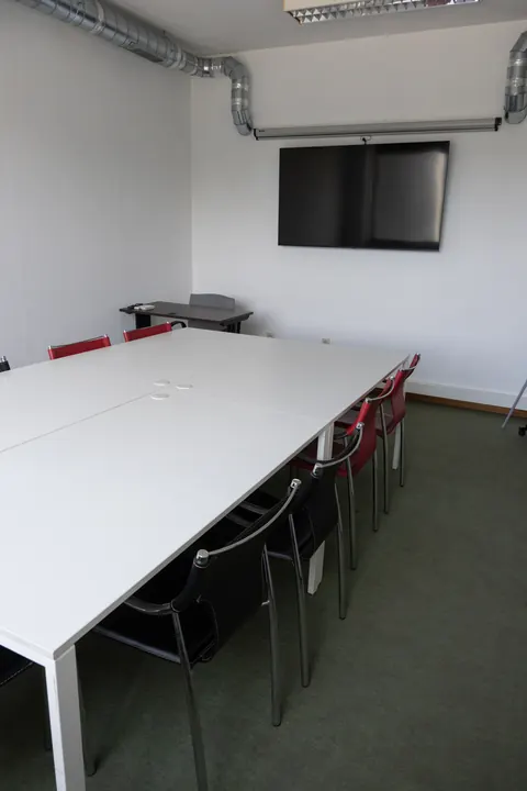 Sala renovada, mesas brancas e cadeiras vermelhas e pretas.